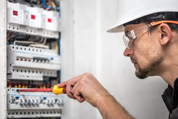 Man, seorang teknisi listrik bekerja di switchboard dengan sekering — Stok Foto