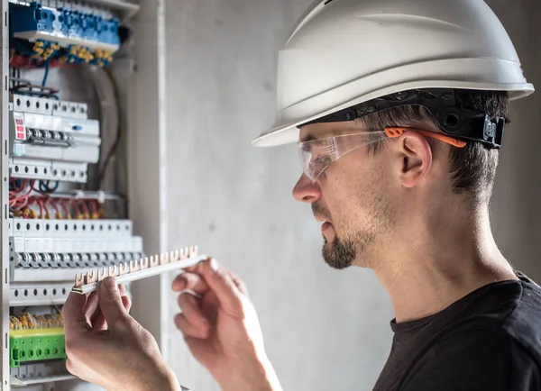 Man, an electrical technician working in a switchboard with fuse