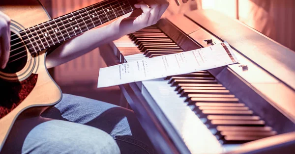 Hombre tocando la guitarra acústica y el piano de cerca, grabando notas — Foto de Stock