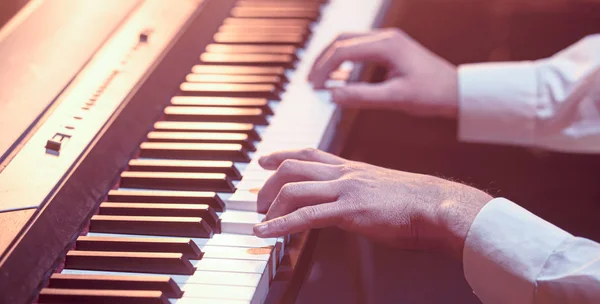 Manos masculinas en las teclas de piano primer plano de un hermoso bac colorido — Foto de Stock