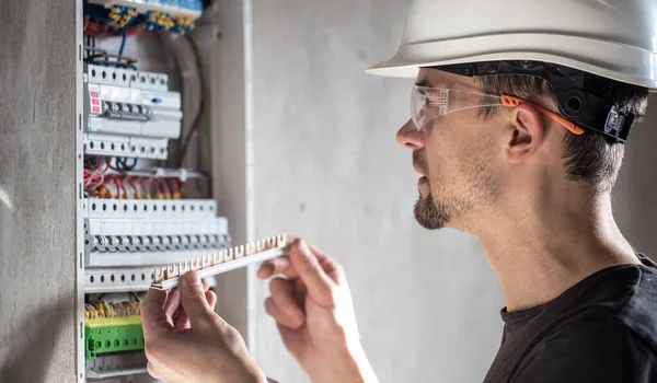 Man, een elektrotechnicus die werkt in een schakelbord met zekering — Stockfoto