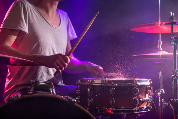 The drummer plays the drums. Beautiful blue and red background, 