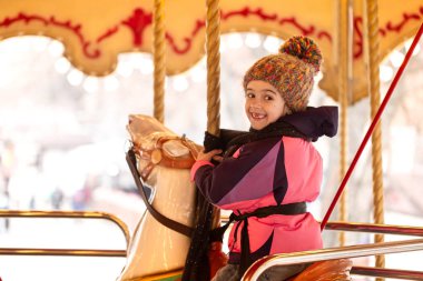 Küçük bir kız atlı karıncaya biniyor, kış tatilinde..