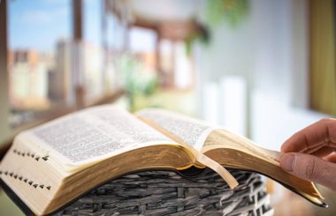 A man holds a Bible and reads a book on the terrace. Morning tim