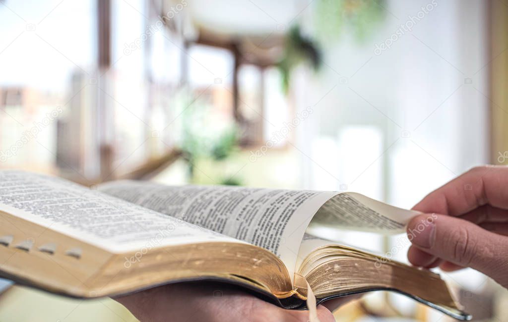 A man holds a Bible and reads a book on the terrace. Morning tim