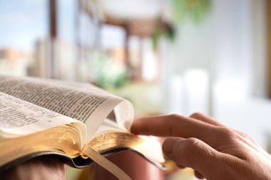 A man holds a Bible and reads a book on the terrace. Morning tim