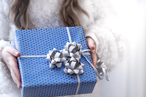 Una niña pequeña sosteniendo un regalo de vacaciones azul . — Foto de Stock