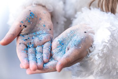 Mavi pullu küçük bir kızın elleri.