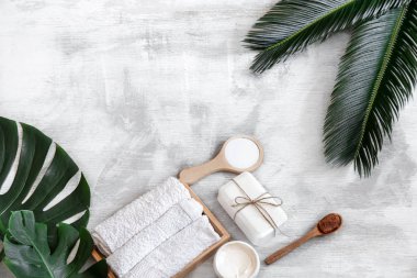 Spa mı? Beyaz arka planda tropikal yapraklı vücut bakımı ögeleri.