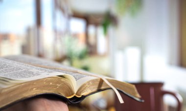 A man holds a Bible and reads a book on the terrace. Morning tim