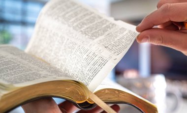A man holds a Bible against the background of the living room. R