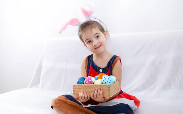 Malá roztomilá dívka s velikonočními vejci a zajíčky uši . — Stock fotografie