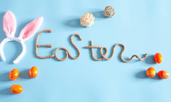 Easter creative inscription on a blue background with items of Easter decor. The concept of the Easter holiday.