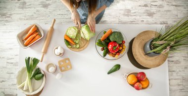 Genç ve güzel bir kadın mutfakta çeşitli sebzelerden oluşan bir salata hazırlıyor. Sağlıklı beslenme ve yaşam tarzı kavramı.