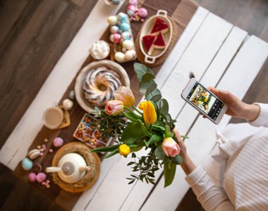 Paskalya tatili. Telefonunuzdaki fotoğraf, güzel korunmuş bir masa, bayramlık Paskalya yemeği ya da kahvaltı için. Aile değerleri ve Paskalya tatili kavramı. en üstteki görünüm