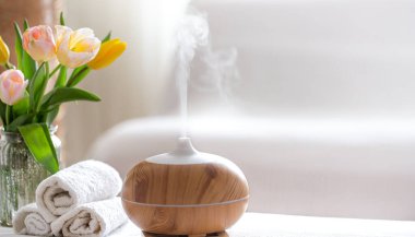 Vücut bakım ürünleriyle modern yağ yayıcı aromalı spa kompozisyonu. Bükülmüş beyaz havlular, bahar yeşillikleri ve çiçekler. Vücut ve sağlık hizmetleri için spa konsepti .