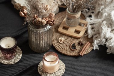 İç dekoratif detaylarla dolu sakin bir ev. Ev eşyaları ve konfor. Mumlar ve kitap oturma odasındaki yatağın üzerinde yatıyor..