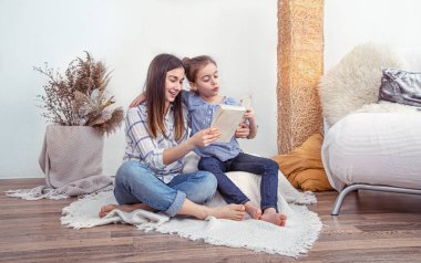 Annem tatlı kızıyla birlikte evde bir kitap okuyor. Çocukların gelişimi ve eğitimi, aile değerleri. Çocuk arkadaşlığı ve aile kavramı. .