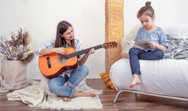 Annem evde kızlarıyla oynuyor. Müzik aleti dersleri, gitar. Çocuk gelişimi ve aile değerleri. Çocuk arkadaşlığı ve aile kavramı. .