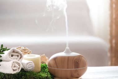 Vücut bakım ürünleriyle modern yağ yayıcı aromalı spa kompozisyonu. Bükülmüş beyaz havlular, bahar yeşillikleri ve çiçekler. Vücut ve sağlık hizmetleri için spa konsepti .