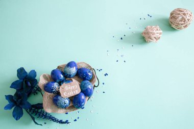 Mavi arka planda renkli yumurta ve çiçeklerden oluşan yaratıcı Paskalya düzeni. Daire şeklinde düz çelenk konsepti. Paskalya tatili konsepti.