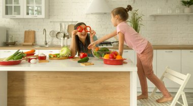 Anne ve kızı mutfakta bir salata hazırlayın. İyi eğlenceler ve sebzelerle oynayın. Sağlıklı beslenme ve yaşam tarzı kavramı. Vejetaryen beslenme ve sağlıklı bir yaşam tarzı..