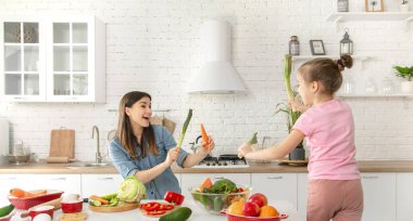 Anne ve kızı mutfakta bir salata hazırlayın. İyi eğlenceler ve sebzelerle oynayın. Sağlıklı beslenme ve yaşam tarzı kavramı. Vejetaryen beslenme ve sağlıklı bir yaşam tarzı. Aile değeri .
