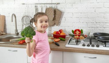 Mutfakta sebzeleri olan tatlı küçük bir kız. Sağlıklı beslenme ve yaşam tarzı kavramı. Aile değeri .