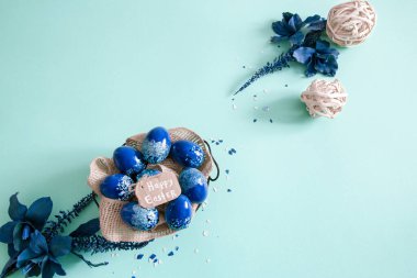 Mavi arka planda renkli yumurta ve çiçeklerden oluşan yaratıcı Paskalya düzeni. Daire şeklinde düz çelenk konsepti. Paskalya tatili konsepti.