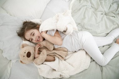 Sevimli küçük bir kız oyuncak bir ayıyla yatakta uyuyor. Çocuk gelişimi ve uyku kavramı. Yukarıdan görünüşü.