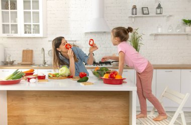Anne ve kızı mutfakta bir salata hazırlayın. İyi eğlenceler ve sebzelerle oynayın. Sağlıklı beslenme ve yaşam tarzı kavramı. Vejetaryen beslenme ve sağlıklı bir yaşam tarzı. Aile değeri .