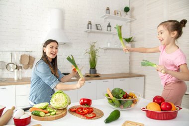 Anne ve kızı mutfakta bir salata hazırlayın. İyi eğlenceler ve sebzelerle oynayın. Sağlıklı beslenme ve yaşam tarzı kavramı. Vejetaryen beslenme ve sağlıklı bir yaşam tarzı. Aile değeri .