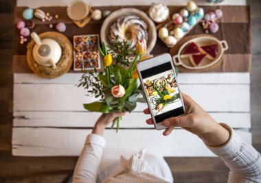 Paskalya tatili. Telefonunuzdaki fotoğraf, güzel korunmuş bir masa, bayramlık Paskalya yemeği ya da kahvaltı için. Aile değerleri ve Paskalya tatili kavramı. en üstteki görünüm