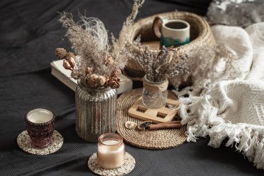 İç dekoratif detaylarla dolu sakin bir ev. Ev eşyaları ve konfor. Mumlar ve kitap oturma odasındaki yatağın üzerinde yatıyor..