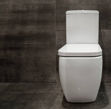 Beyaz tuvaletli, siyah grafit duvarlı bir banyo. Kapat..