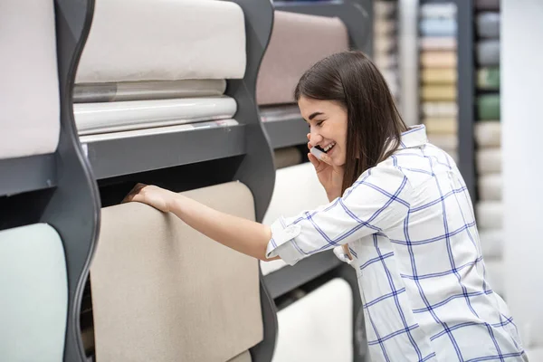 A young woman in a store chooses Wallpaper for her home. Concept of repair and shopping.