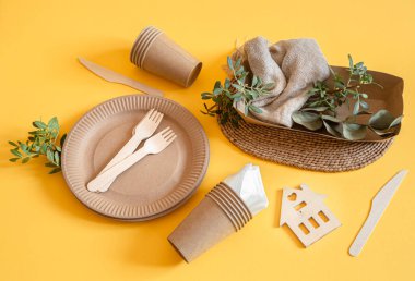 Çevre dostu, şık geri dönüşümlü kağıt sofra takımı. Turuncu arka planda kağıt yiyecek kutuları, tabaklar ve mısır nişastası..