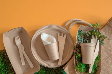 ECO craft paper tableware. Paper cups, plates, bag, fast food containers and wooden Cutlery with cornstarch on a colored orange-blue background. Recycling or the concept of zero waste. clipart