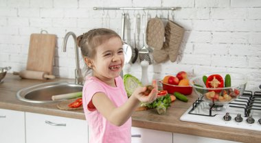 Mutfakta sebzeleri olan tatlı küçük bir kız. Sağlıklı beslenme ve yaşam tarzı kavramı. Aile değeri .