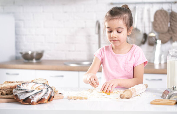 A cute little girl is cooking homemade cakes in the kitchen. Children's development and family values.Healthy diet.