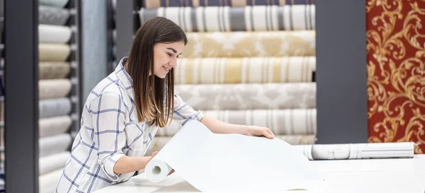 A young woman in a store chooses Wallpaper for her home. Concept of repair and shopping.