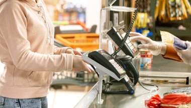 Bir kadın telefonundan kasadaki dükkanın kredisini kullanıyor. Modern teknoloji kavramı.