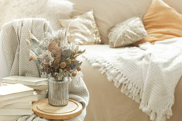 Home cozy interior of the room with books and dried flowers in a vase. The concept of home entertainment.