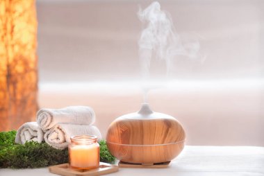 Vücut bakım ürünleriyle modern yağ yayıcı aromalı spa kompozisyonu. Bükülmüş beyaz havlular, bahar yeşillikleri ve çiçekler. Vücut ve sağlık hizmetleri için spa konsepti .
