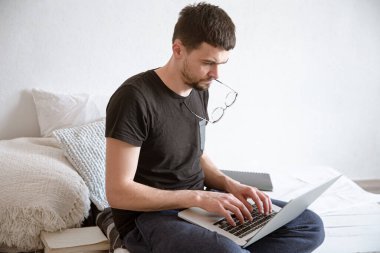 Genç bir adam evdeki bir bilgisayarın başında uzaktan çalışıyor. Serbest Çalışan ve İnternette Çalışan.