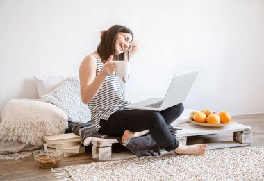 A young woman works remotely at a computer at home. Freelancer and work on the Internet. clipart