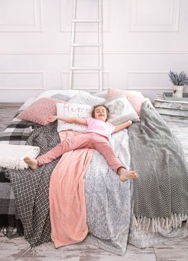 Yatakta oynayan tatlı küçük kız. Üst manzara, eğlen ve uzan.