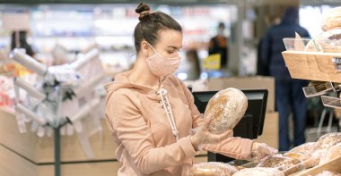 A young woman shopping in a supermarket during a virus epidemic. Wears a mask on his face. clipart