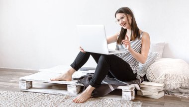 Genç bir kadın evdeki bir bilgisayarın başında uzaktan çalışıyor. Serbest Çalışan ve İnternette Çalışan.