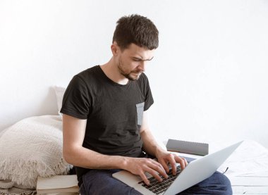 Genç bir adam evdeki bir bilgisayarın başında uzaktan çalışıyor. Serbest Çalışan ve İnternette Çalışan.